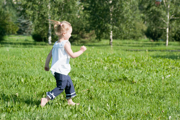 girl runs around the green grass in the park