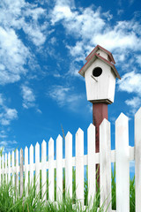 birdhouse white fence and blue sky