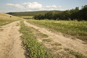 Dirt road in the countryside surrounded by hills and woods