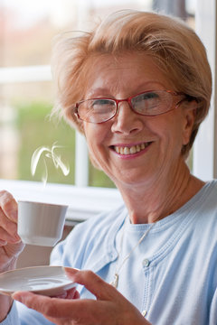 jolie femme retraitée devant sa tasse de café chaud