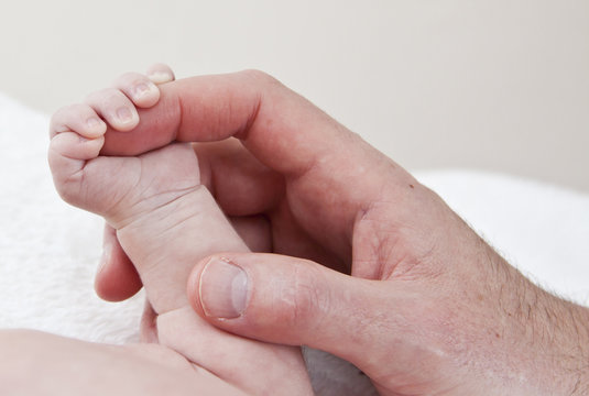 Father holding hand of small baby in colour