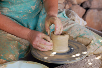 Fototapeta na wymiar close up of the hands of a potter creating a jug on the circle
