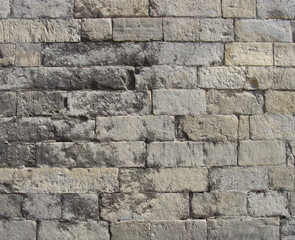 worn very old large stone wall in gray and beige