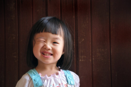 Happy Cute Young Girl Wink With Wooden Background