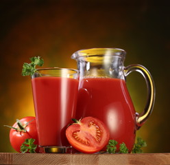 Jug and glass full of tomato juice.