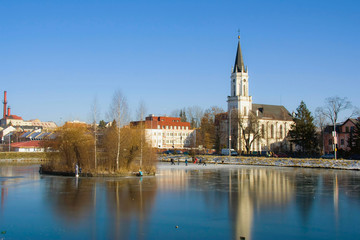 Frozen pond with many skaters with gotical church background