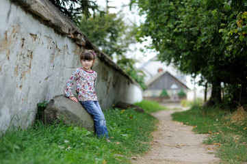 Nice toddler girl near the wall of catholic church