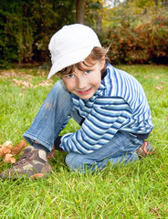 Naklejka na ściany i meble portrait of cute blue-eyed boy in autumn colored park