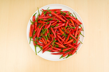 Hot peppers in the plate on wooden table