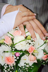 Obraz na płótnie Canvas Hands of newly-married couple on a wedding bouquet