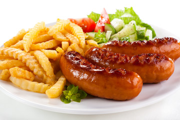 Grilled sausages, French fries and vegetables
