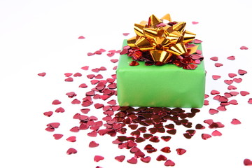 Gift with a gold bow decorated with heart shaped confetti