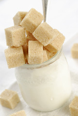 Morceaux de sucres roux débordants d'un yaourt nature