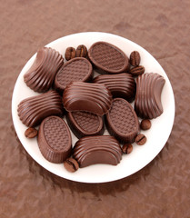 Assorted chocolate candies on brown background