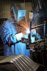 Welder welding a metal part in an industrial factory