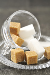 Morceaux de sucre blanc et sucre roux dans une tasse transparente