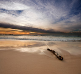 sunrise on beach with log in foreground on square format