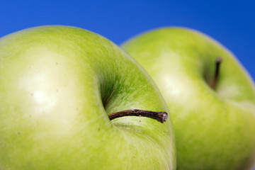 two appetizing apples of green on blue background