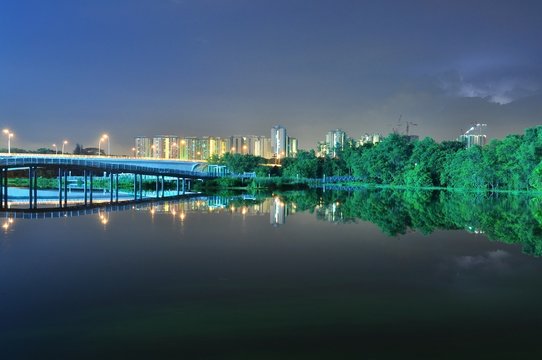 bridges, greenery, buildings and their reflection on a river