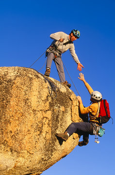 Rock climbing team reaching the summit.