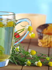 Fresh chamomile tea and flowers with muffin and candle