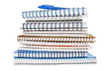 Stack of spiral notebooks with a blue pen