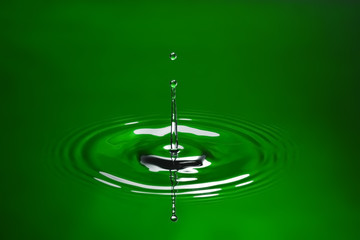 Green water drop splashing in water. - 27316075