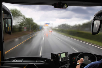 front window of bus and rainy road