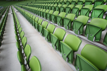 Naklejka premium Rows of folded, green, plastic seats in empty stadium.