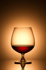 Glass of brandy over gold background