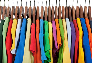 Variety of multicolored clothes on wooden hangers