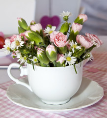 Flowers in a cup on a pink and white table