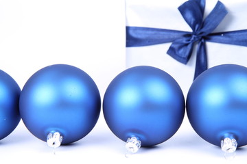 Blue christmas balls and a gift on white, with space for text