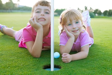 Golf sister girls relaxed laying green hole ball