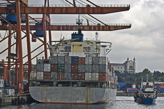 Container cargo ship at industrial port with industrial cranes