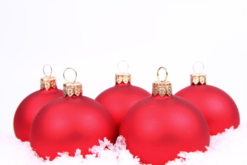 Red matt christmas balls on snow on white,space for your text