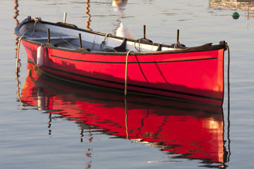 Lumière du matin sur une barque rouge au mouillage