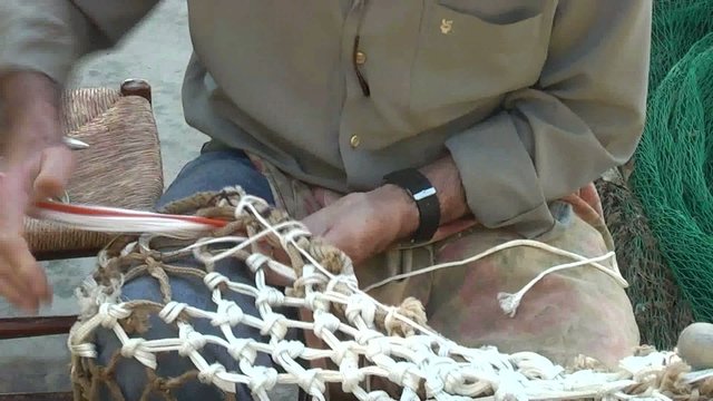 PESCADOR REPARANDO LAS REDES DE PESCA