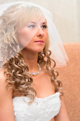 Portrait of young bride with blonde curly hair with veil