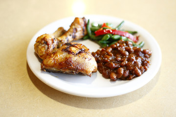 Baked chicken with a side of baked beans and peas