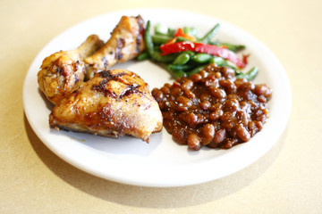 Baked chicken with a side of baked beans and peas