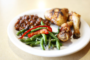 Baked chicken with a side of baked beans and peas