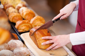 verkäuferin schneidet weckbrot in der bäckerei