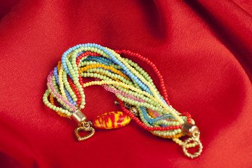 Colorful bracelets and necklaces on red background