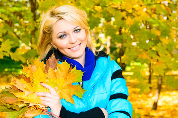 Naklejka na ściany i meble young smiling woman with bunch of maple leaves