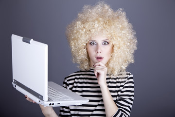 Portrait of funny girl in blonde wig with laptop.