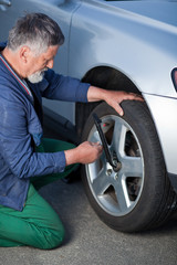 mechanic changing a wheel of a modern car (shallow DOF; color to