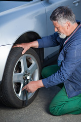 mechanic changing a wheel of a modern car (shallow DOF; color to
