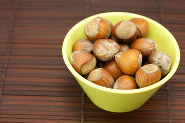 hazelnuts in a bowl on a bamboo mat