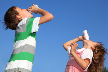 Small boy and the girl against sky, with pleasure drink yoghurt